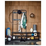 A modern, black metal entryway organizer with a bench, shoe shelf, and coat rack. It has geometric designs and hooks for hanging items.