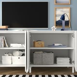 Modern tv stand with adjustable shelves, storing gaming consoles, books, and accessories.