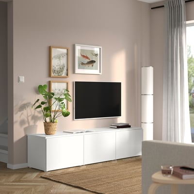 A modern living room with a low white PLATSA tv unit filled with a tv, art, and a plant.