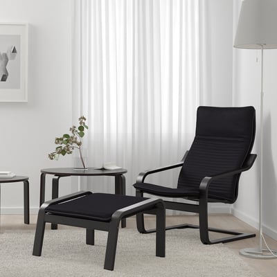 POÄNG black armchair with footstool in minimalist room. Sleek design with cushions and decor for a cosy ambiance.