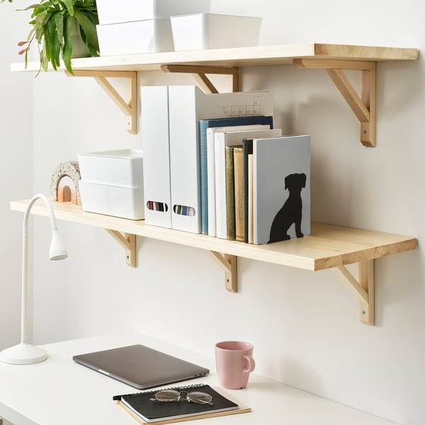 Shelves with books and decor; laptop, mug, and lamp on desk.