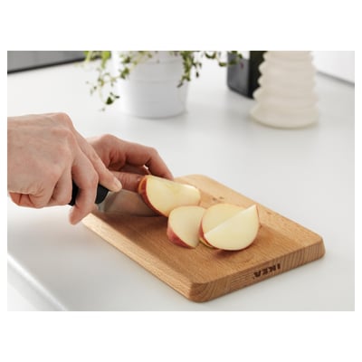 Person slices apple on PROPPMÄTT wooden cutting board.