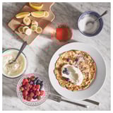 Breakfast scene: pancakes, berries, yogurt, and syrup.