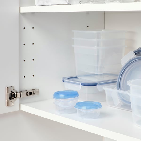 Clear plastic containers with blue lids stacked in a cabinet, held by a metal hinge.