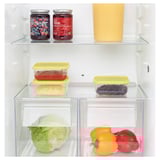 Fridge with stacked food containers, jars, and fresh veggies. Yellow containers store leftovers, saving space.
