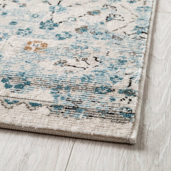 Elegant rug with intricate floral patterns, soft pile, and durable design, placed on a wooden floor.