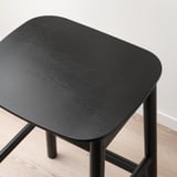 Close-up view of black RÖNNINGE bar stool made from birch veneer and solid wood, showing quality craftsmanship.