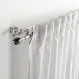 Curtain rod bracket holding rods together. White curtains draped over, displaying connector functionality.