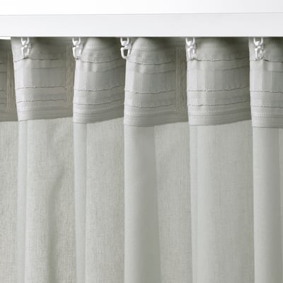 Light grey sheer curtains hang from white hooks, offering privacy while allowing light to filter through.