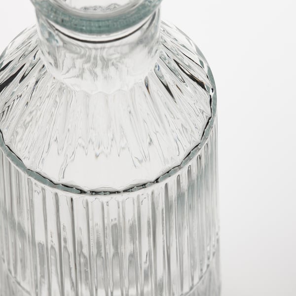 Clear, textured glass carafe with vertical ridges and detailed top, reflecting elegance and quality.