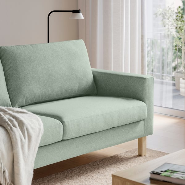 Light green SALTSJÖBADEN sofa with wooden legs, offering a cosy, inviting look and comfortable seating.