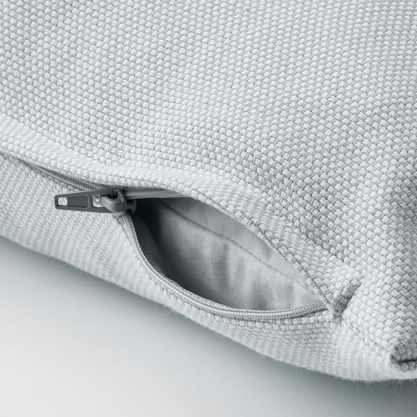 Light blue cushion cover with textured cotton, zipper open for easy removal.