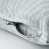 Light blue cushion cover with textured cotton, zipper open for easy removal.