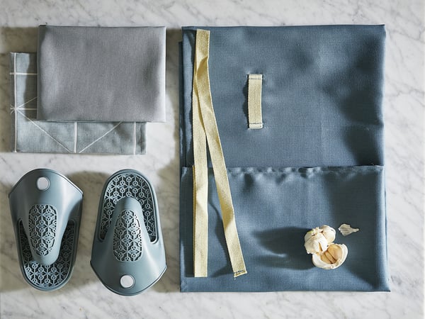 Top view of gray silicone oven mitts, folded and laid flat, with a garlic bulb on the table.