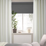 Minimalist bedroom window with off-white curtains, plant, lamp, and radiator.