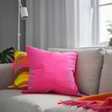 Bright pink SANELA cushion on a neutral sofa, large, plush, square.