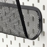 Black metal mesh storage basket on a pegboard system, securely attached with black hooks, designed for organizing items efficiently.