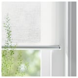 Window with white roller blind partially drawn, showing green plants outside.