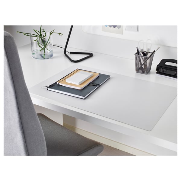 Small white SKRUTT desk pad protects desk, fits neatly under notebooks, beside pen holder.