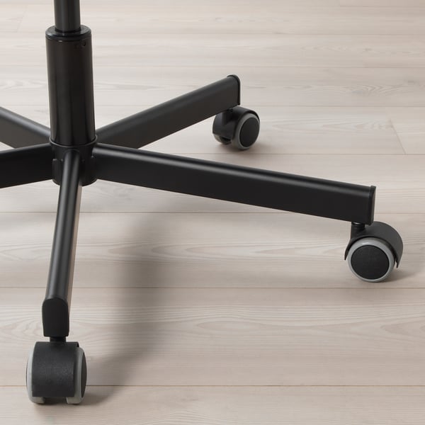 Black office chair base with castors on light wooden floor, showcasing sturdy build and smooth-gliding wheels.
