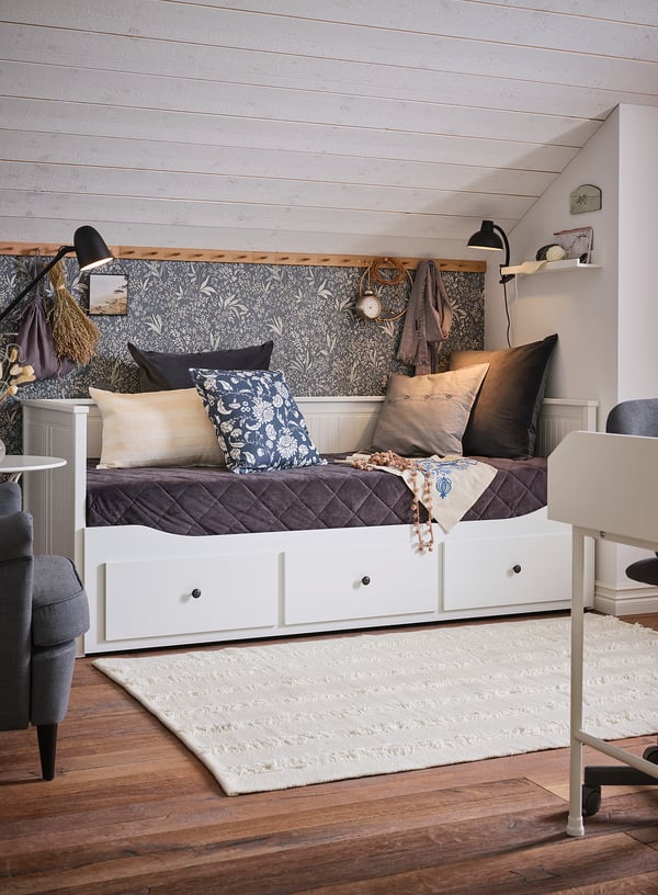 Modern bedroom with white wood floors, a white bed frame, grey cushions, a floral-patterned headboard, and black lamps.