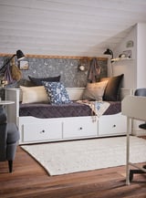 Modern bedroom with white wood floors, a white bed frame, grey cushions, a floral-patterned headboard, and black lamps.