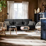 Modern living room with dark gray SLATORP sofa, wooden coffee table, wicker chair, and large window with sheer curtains.