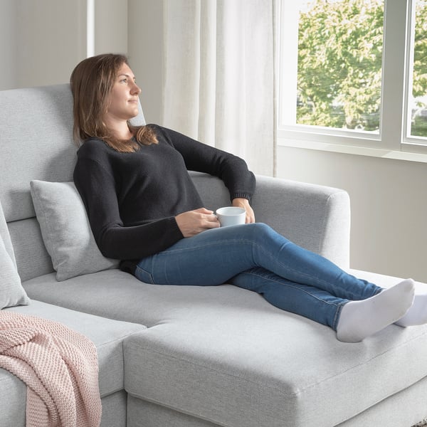 Woman relaxes on adjustable sofa with coffee cup.