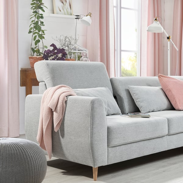 Cozy living room with grey SLATORP sofa, light pink curtains, and plants. Soft cushions and a blanket add comfort.