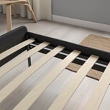 Modern bed frame with wooden slats and padded headboard.