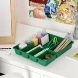 Green SMÄCKER tray organizes art supplies, fitting well on a table.
