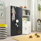 Kids room with SMÅSTAD wardrobe; blackboard door, white drawers, toy storage, colorful rug.