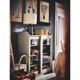 Cozy corner with lamp, glass-cabinet, wicker baskets, & nature prints.