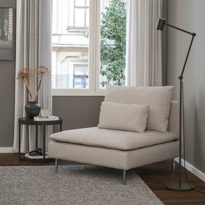 Modern minimalist SÖDERHAMN chair, beige, soft fabric, low profile. Near floor lamp, side table with vase and mug, large window. Cozy corner.