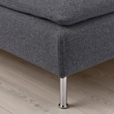 Modern sofa close-up on stylish floor. Dark grey fabric, chrome leg visible.