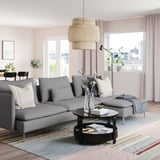 Modern living room with grey SÖDERHAMN sofa, wood floors, city view window, pendant light, and striped rug.