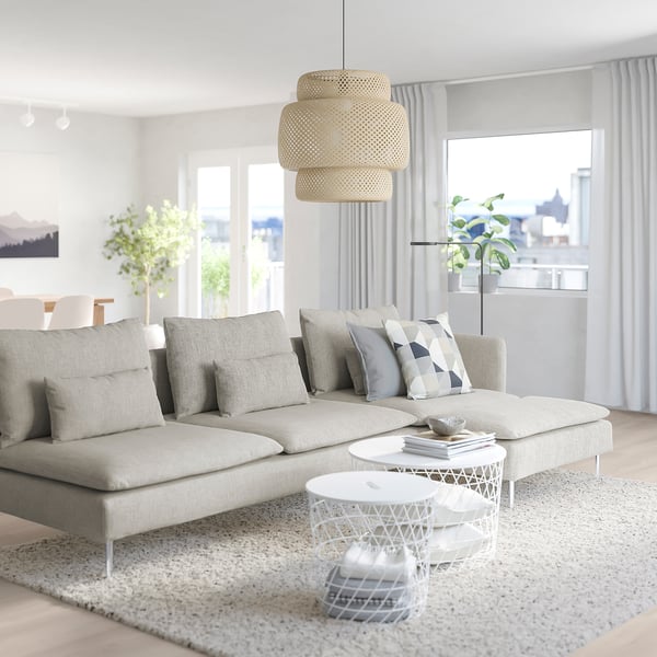 Modern living room with large SÖDERHAMN off-white sectional sofa, grey geometric throw pillows, stacked wicker pendant light, and city view windows.