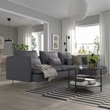Modern living room with SÖDERHAMN sofa, striped rug, coffee table with flowers, dining area, giraffe decor, lamps.