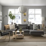 Modern living room with large gray SÖDERHAMN sectional sofa, wooden coffee table, and stylish decor, featuring large windows and a round rug.