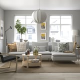 Grey SÖDERHAMN sofa set, deep-seated, with large cushions and round wooden table by a large window with city views.
