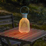 Solar lantern on wooden table, illuminating outdoors.