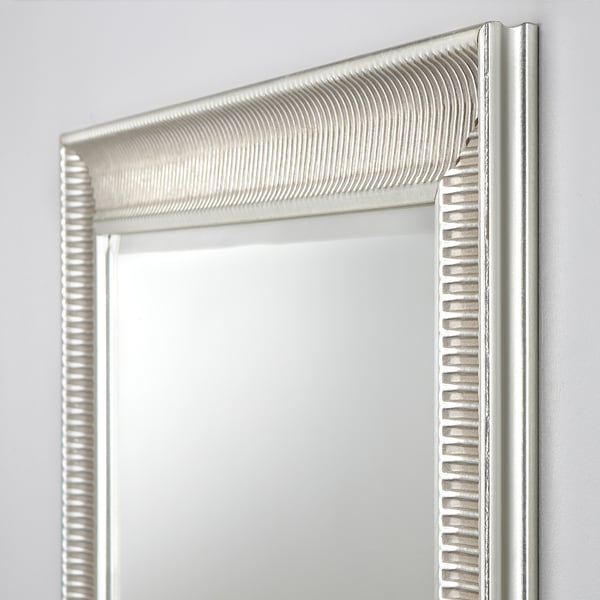 Ornate mirror with intricate textured frame, reflecting crisply. Shows subtle signs of aging, adding vintage charm. Mounted securely on a plain wall.