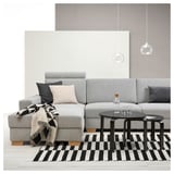 Modern gray sofa with black and white striped rug, glass coffee table, and hanging lamps.