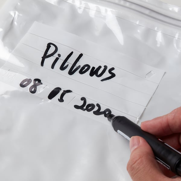 Hand writes pillows 08/01/2020 on bag, showcasing SPANTAD storage bags usage for labeling and organizing.