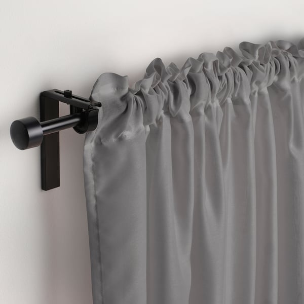 Light grey sheer curtains hang from modern matte black rod, gently diffusing daylight.