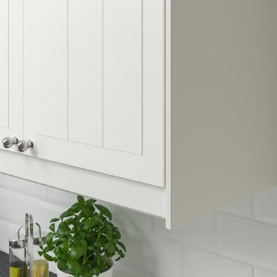 White kitchen cabinet with silver handles and under-cabinet lighting, featuring a green plant and oil dispensers on the countertop.
