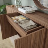 Wooden chest with open drawer revealing folded fabrics and magazines.