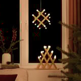 Cozy pine pendant and table lamp duo, battery-operated, emitting warm white light, sitting on a window sill beside a christmas tree.
