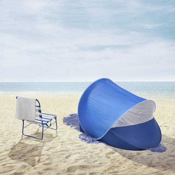 Blue STRANDÖN beach pop-up shelter on sand, smaller than chair, with mesh for ventilation.