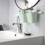 Modern sink with tall green organizer holding toiletries.
